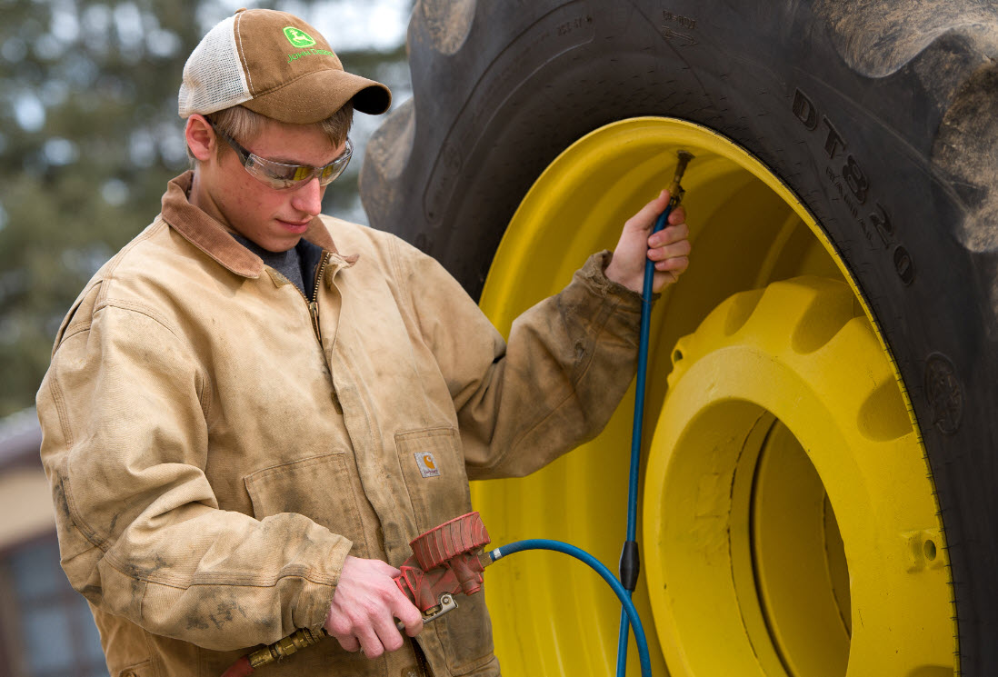 Image of boy putting air in tractor tire